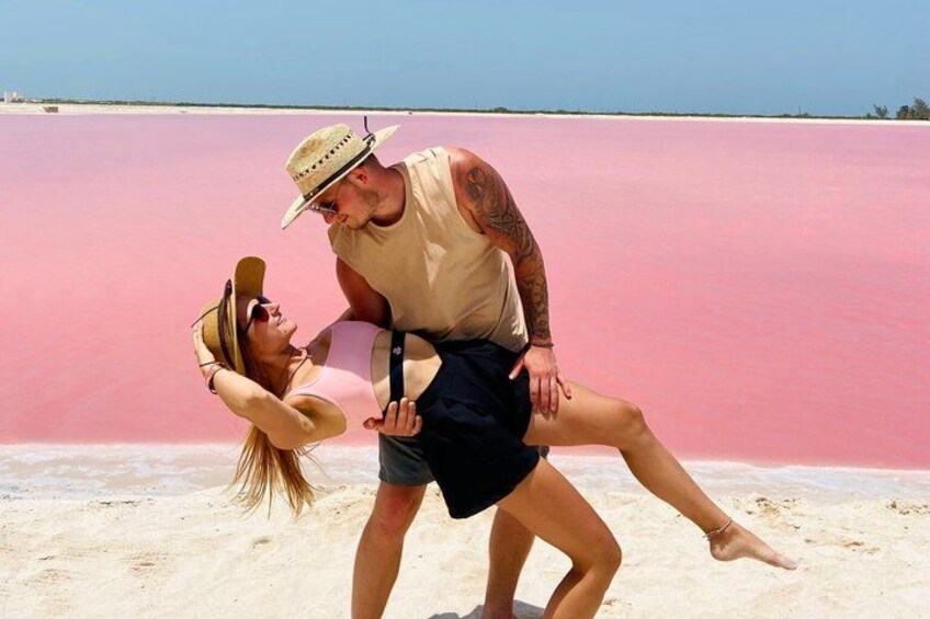 A couple on a beach with a pink wall in the background. 1