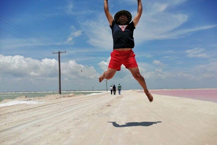 A person jumping on a beach with a pink sand area in the background. 4