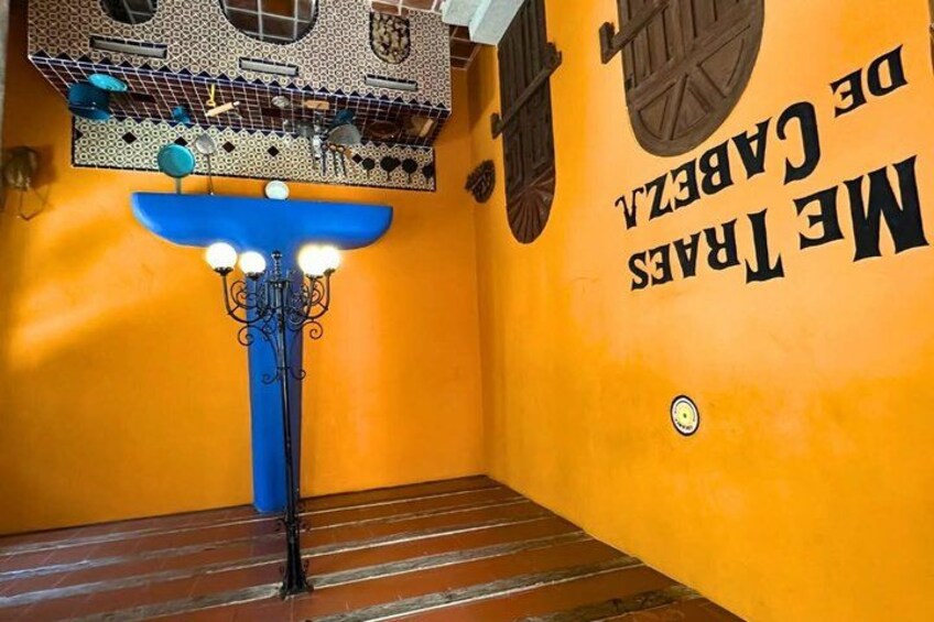 A room with a blue chandelier, a wooden floor, and a wall with text. 3