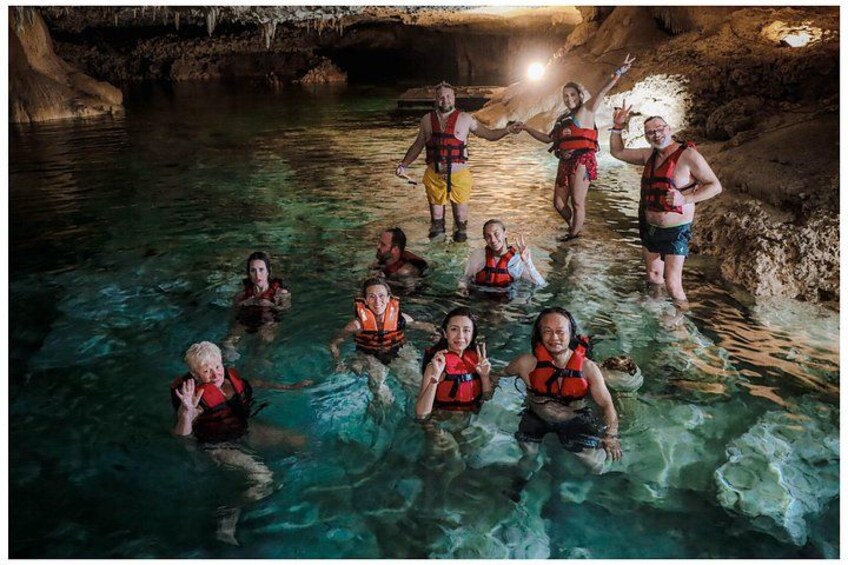 People in a cave with clear water, wearing life jackets. 2