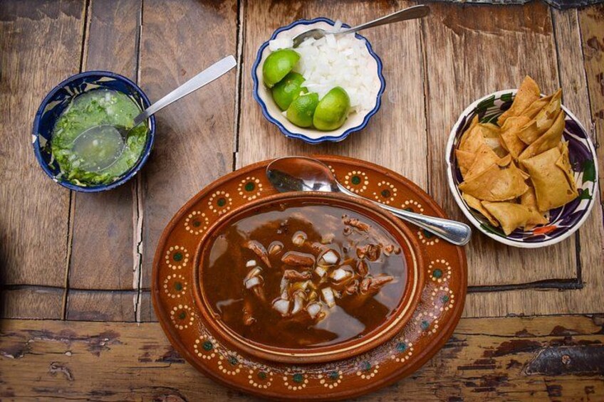 A traditional Mexican meal with a bowl of soup, rice with lime, and tortilla chips. 3