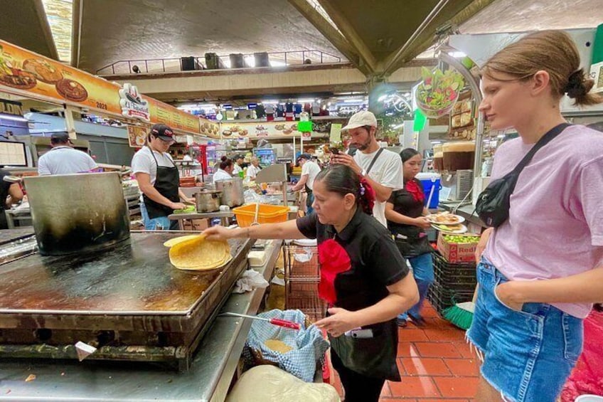 A bustling food market with people cooking and serving food. 2