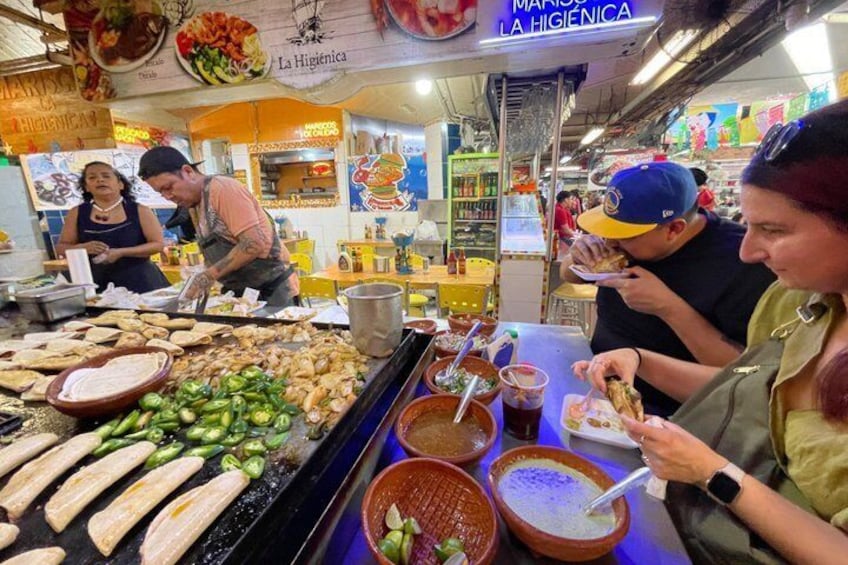 A street food stall with grilled meats, vegetables, and sauces. 1