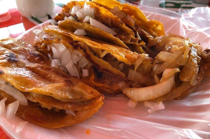 A plate of tacos with grilled onions and a tortilla. 4