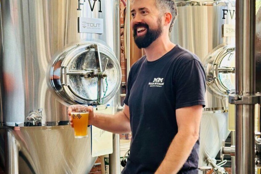 Une personne tenant un verre de bière devant un robinet sur lequel est inscrit « FVI STOUT ». 4
