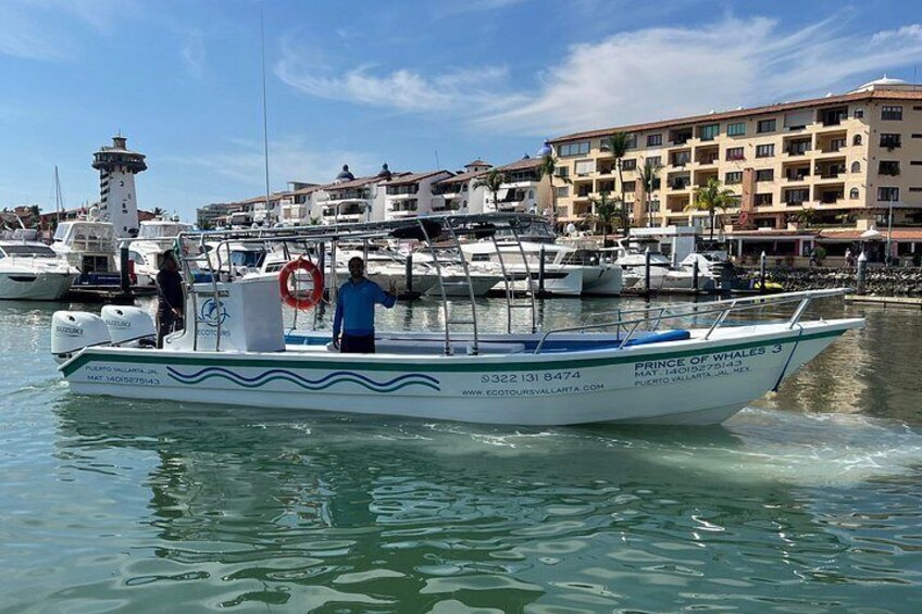 A boat named 'PRINCE OF WHALES 3' on calm water with a marina and buildings in the background. 2