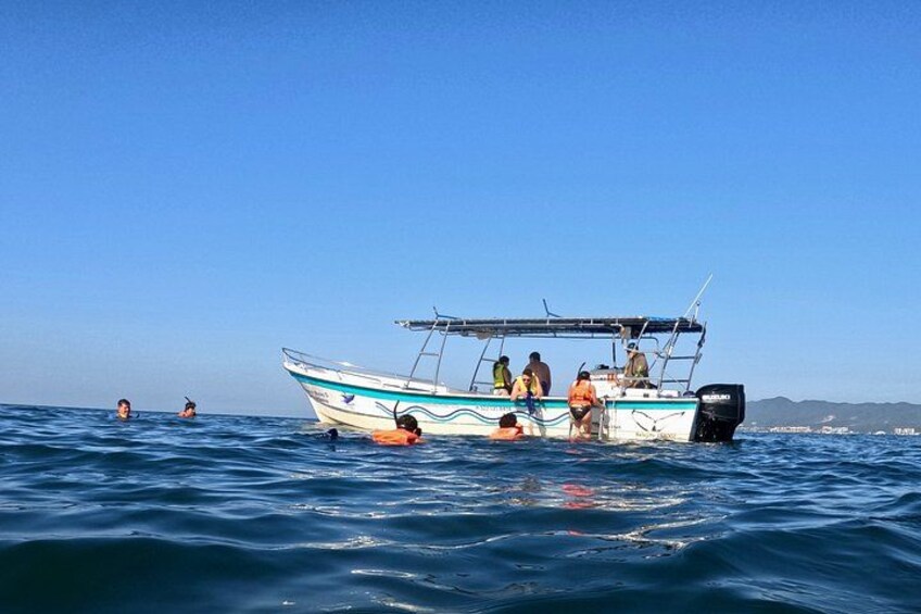 Un bateau avec des personnes à bord et des nageurs dans l’eau. 4