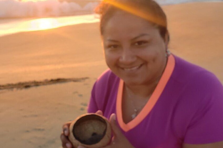 A person holding a wooden bowl on a sandy beach. 3
