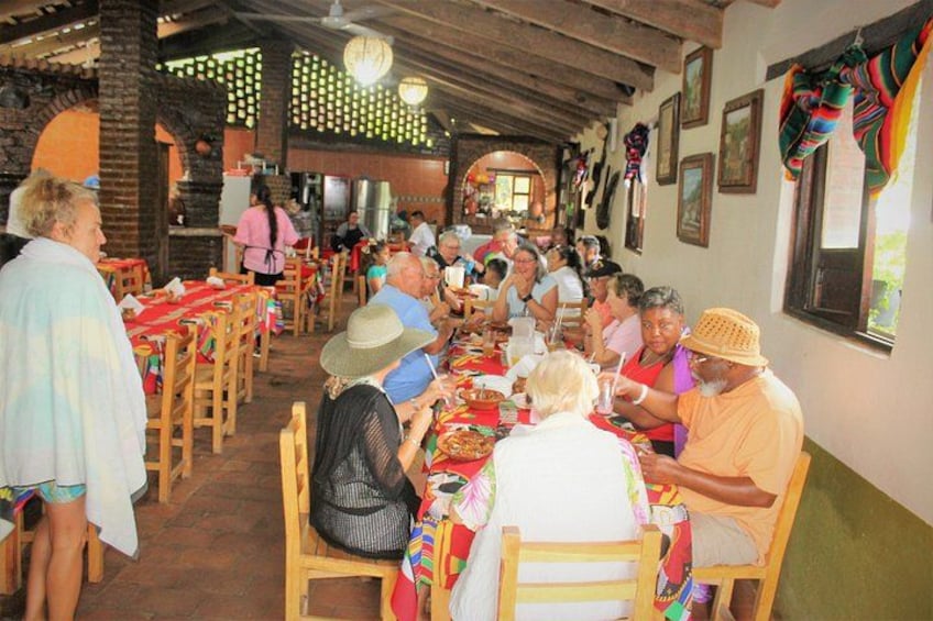 Un ristorante con tavoli e sedie di legno, persone che cenano e decorazioni colorate alle pareti. 5