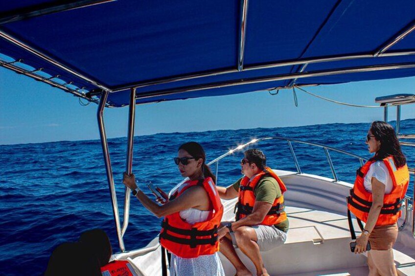 En båd med tre personer i redningsveste sejler på havet. 1