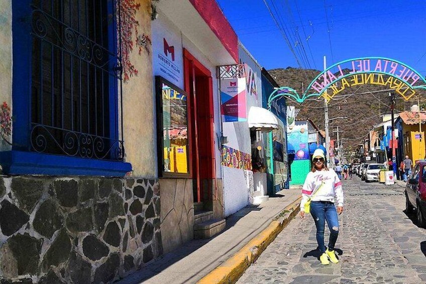 A cobblestone street with colorful buildings, a person standing on the sidewalk, and a sign that reads 'BUENOS AIRES.' 5