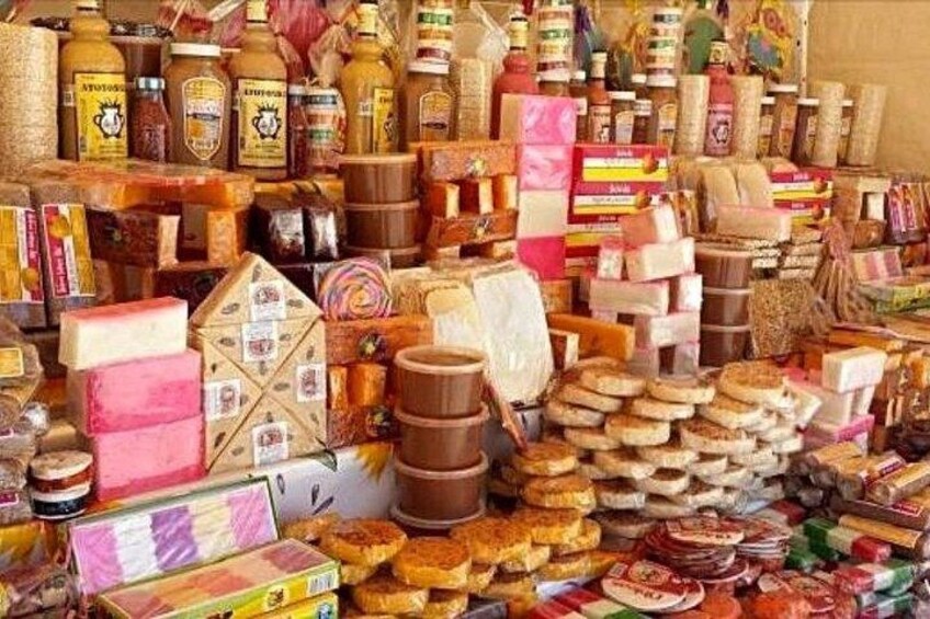 A variety of cheeses, honey, and other food items displayed at a market stall. 3