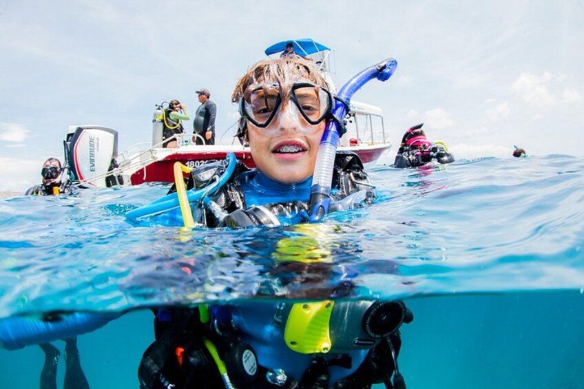 A person underwater with scuba gear, surrounded by boats and other divers. 5