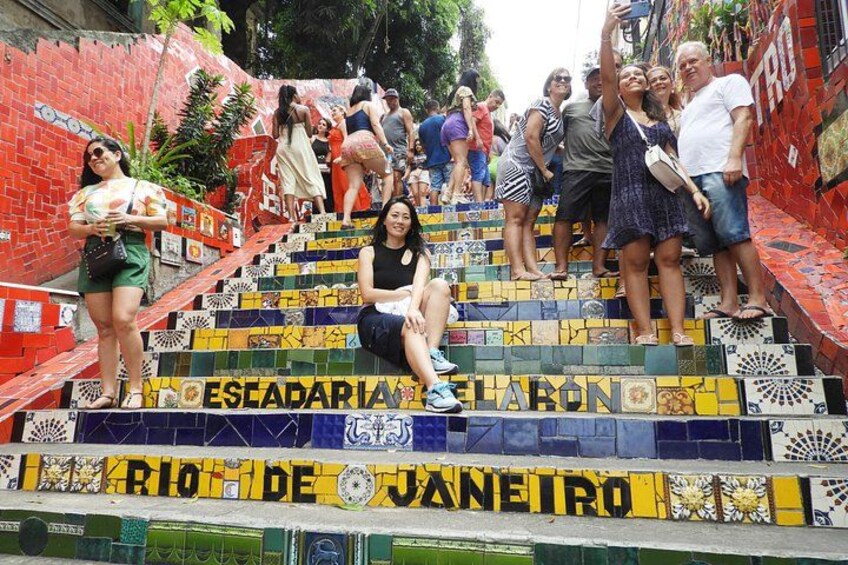 Un gruppo di persone su gradini colorati in maiolica, con la scritta 'Rio de Janeiro' ben visibile. 1