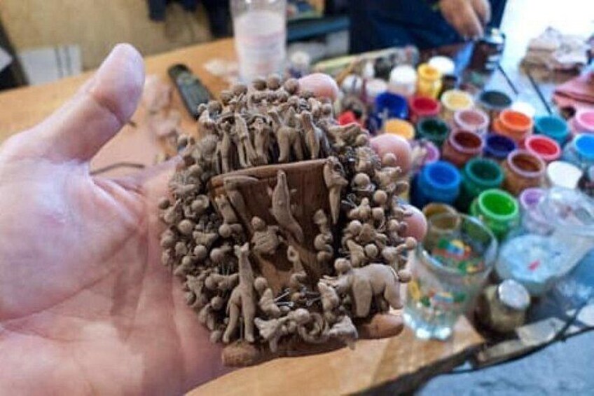 En hånd holder en detaljeret skulptur af en menneskemængde. 2