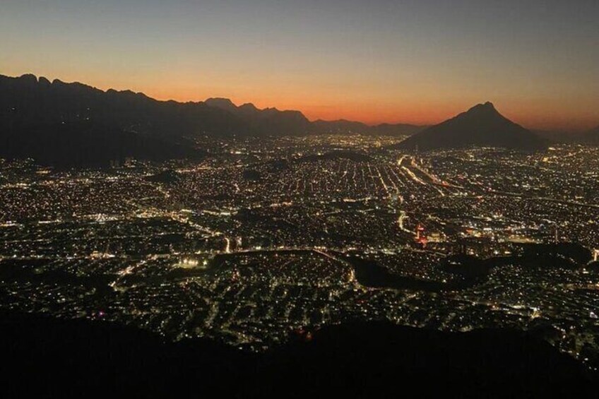 A cityscape at dusk with a mountain in the background. 1