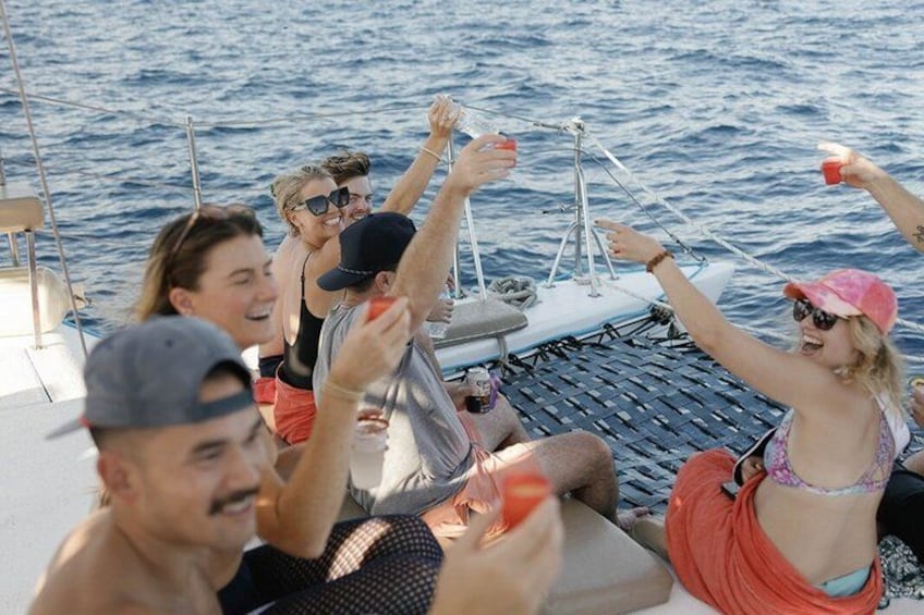 A group of people on a sailboat, holding drinks and toasting. 5