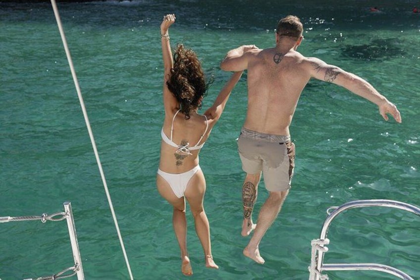 Two people jumping into clear blue water from a boat. 4