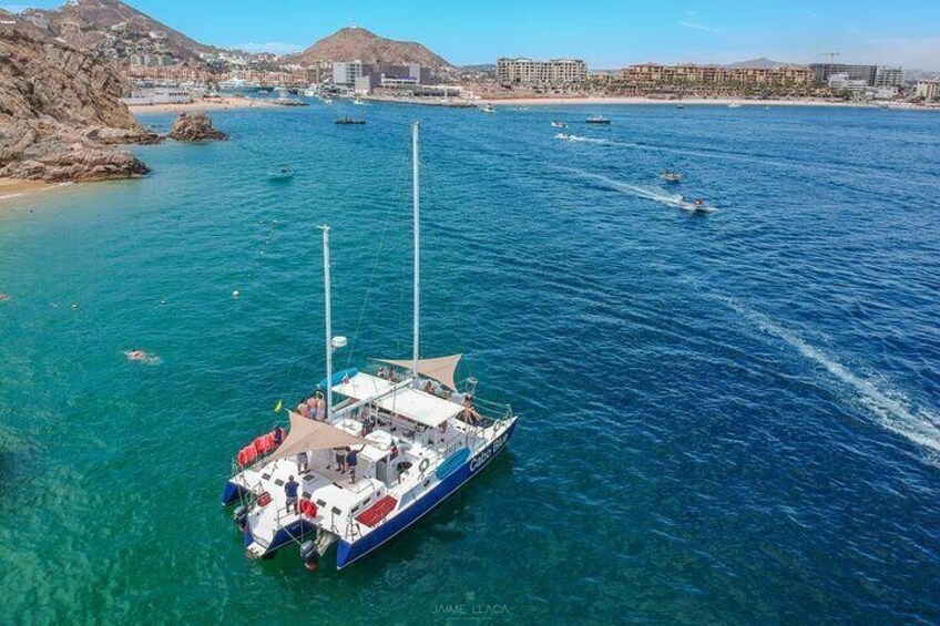 A sailboat anchored in a clear blue harbor with buildings in the background. 1