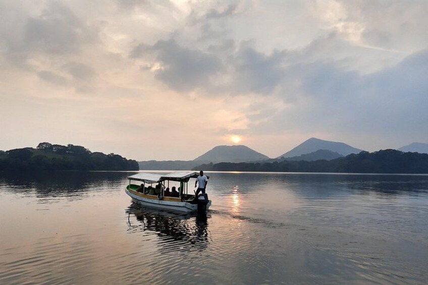 A boat on calm water with mountains in the background and a setting sun. 1
