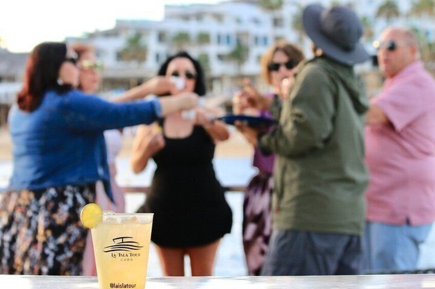 A group of people on a beach, a drink with a label, and a building in the background. 4