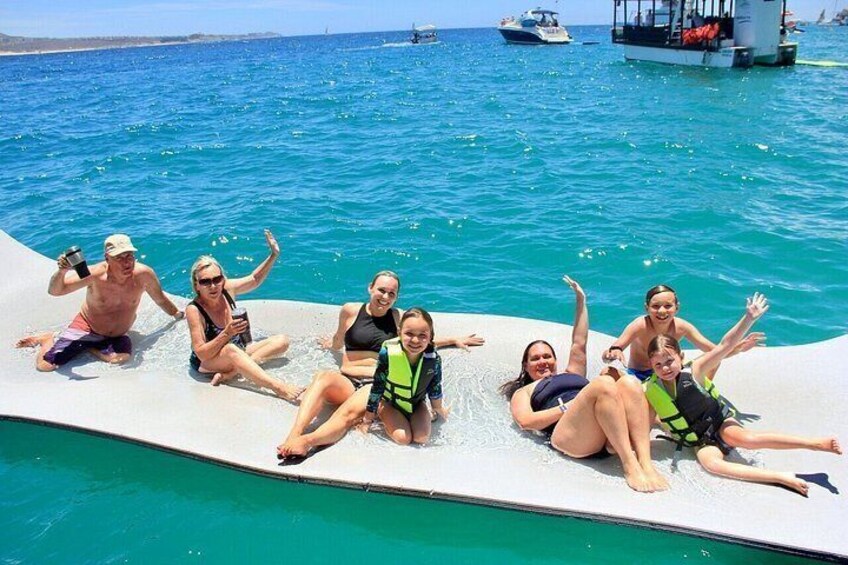 A group of people on a floating platform in a body of water with boats in the background. 5