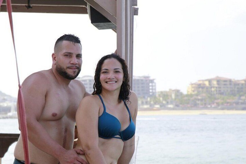 A man and a woman on a boat with a cityscape and beach in the background. 5