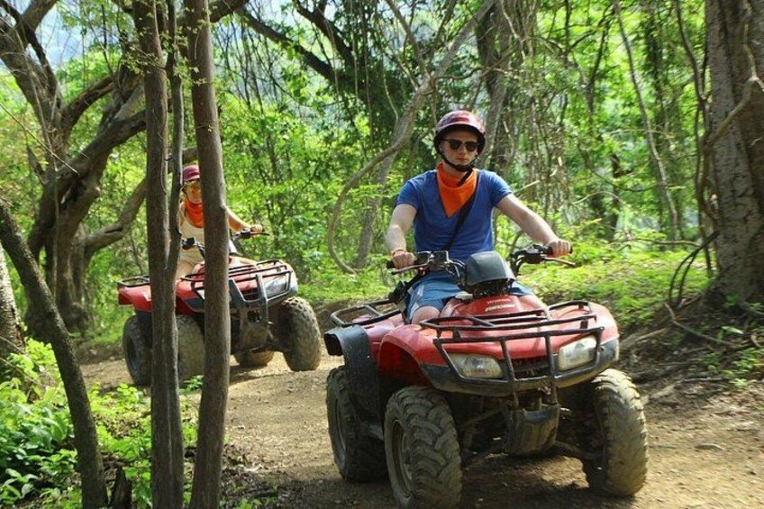 Two people riding ATVs on a forest trail. 3