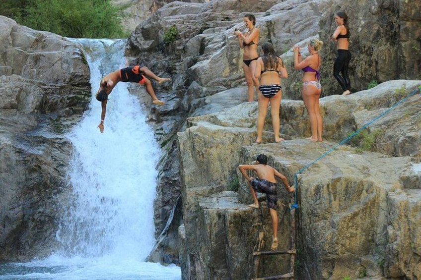 A waterfall, rocky terrain, and people engaging in water activities. 2