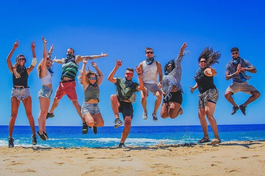 A group of people jumping on a beach with the ocean in the background. 5