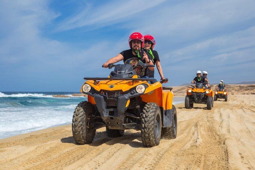 A sandy beach with vehicles and people. 1