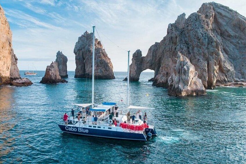 A boat named Cabo Blue sailing near rocky formations with a clear sky. 2