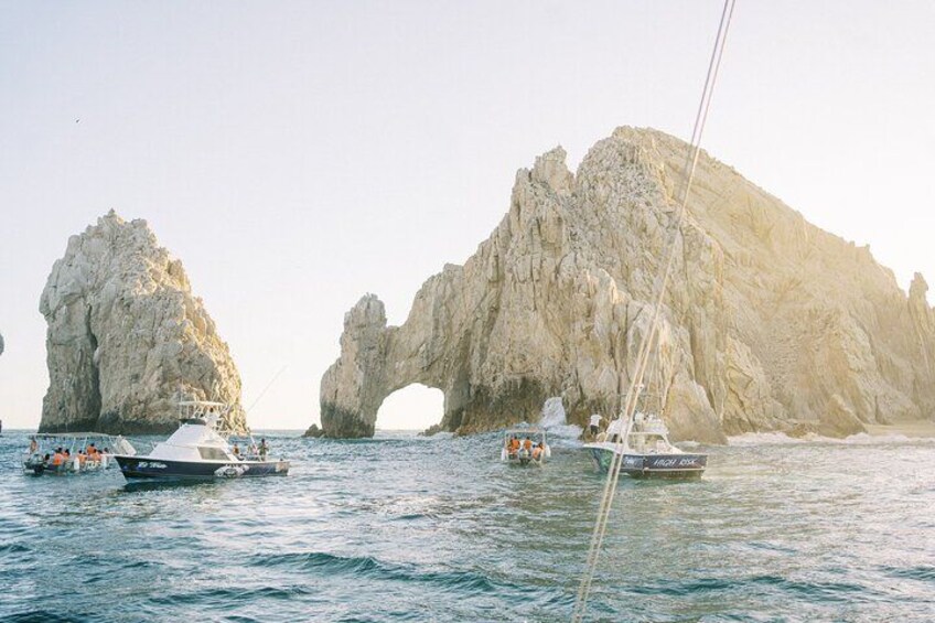 A coastal scene with boats, rocky cliffs, and a natural arch formation. 5
