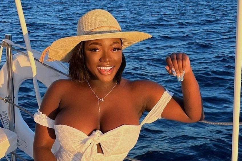 A person on a boat with a lifebuoy, wearing a straw hat and a white off-shoulder top. 5