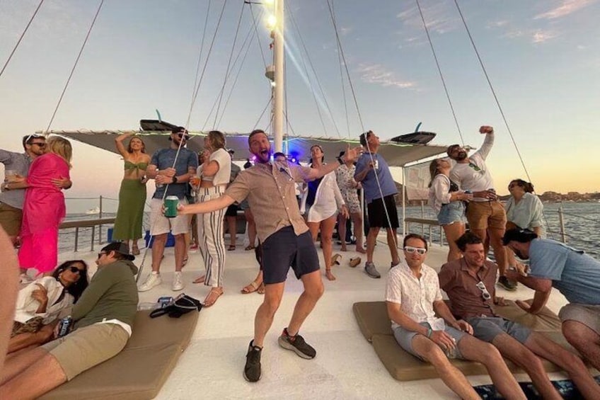 A group of people on a boat, some standing and some sitting, with a clear sky in the background. 3