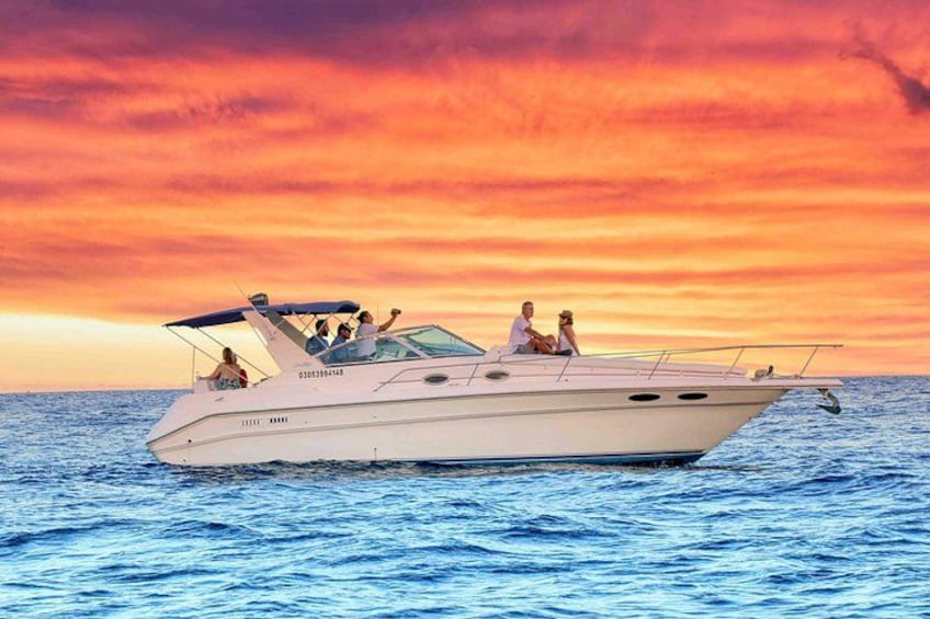 A white motorboat on the water with a sunset in the background. 1