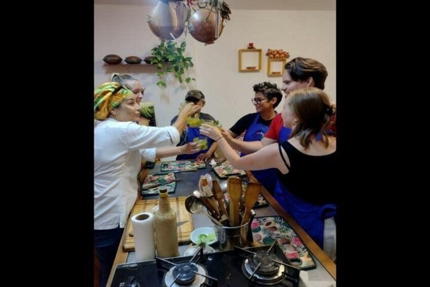 A group of people gathered around a table with cooking utensils and ingredients, engaged in a cooking activity. 2