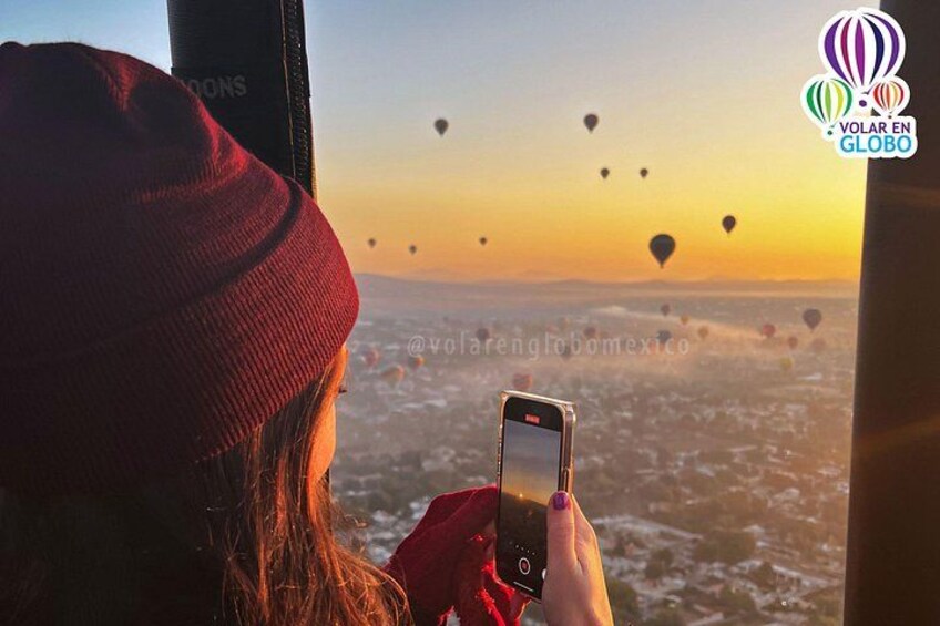 Una persona fotografiando globos aerostáticos al atardecer. 3