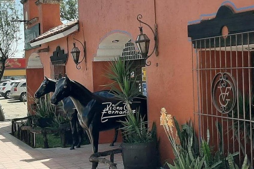A building with a horse statue and a gate with a logo. 3