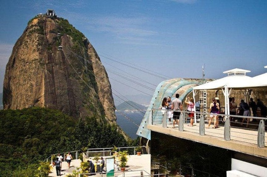 A large rock formation with a viewing platform and people. 1