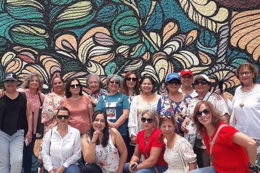 A group of people posing in front of a colorful mural. 4