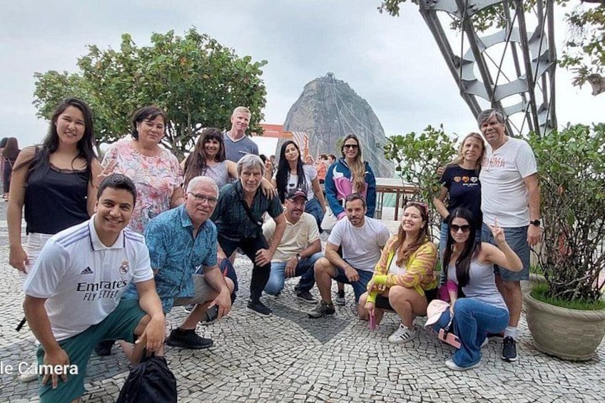 A group of people posing for a photo in an outdoor setting with a rocky ground and a large rock formation in the background. 3