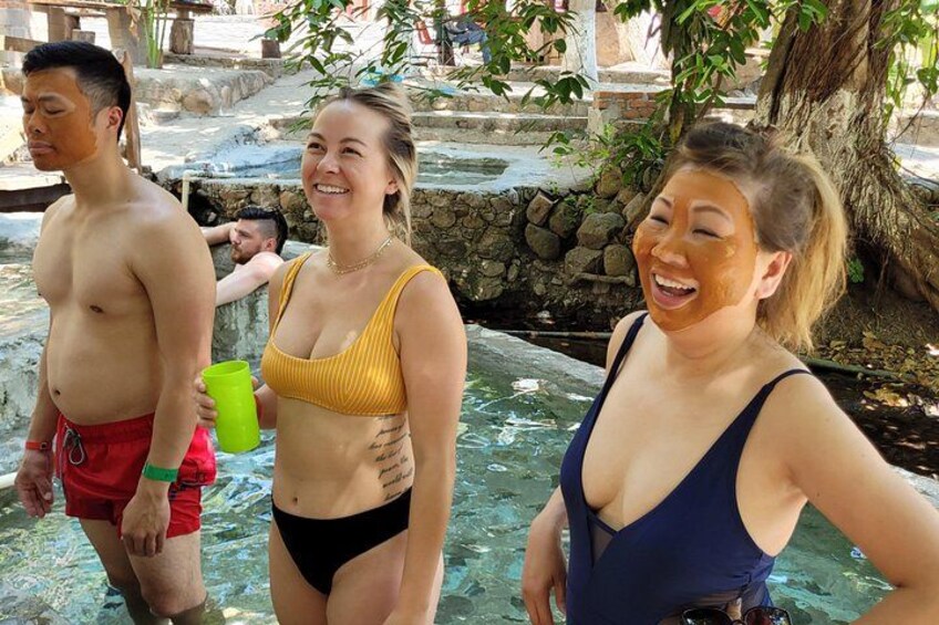 Persone in costume da bagno vicino a un corpo d'acqua, una parete di pietra e un albero. 3