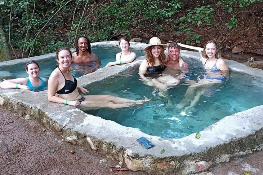 Un groupe de personnes se trouve dans une source d’eau chaude naturelle, entourée d’arbres. 3