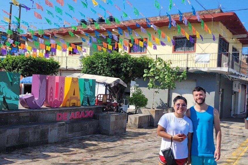 Una strada con bandiere colorate, un edificio con insegna 'DE ABAJO' e un grande cartello con la scritta 'VIVA'. 5