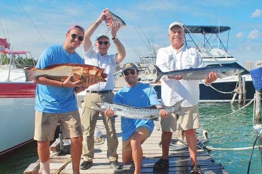 A group of people on a dock holding fish. 2