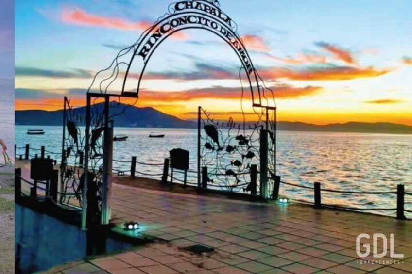 A sunset at a waterfront with a metal archway labeled 'Chapel de la Concepcion de la Mer.' 1
