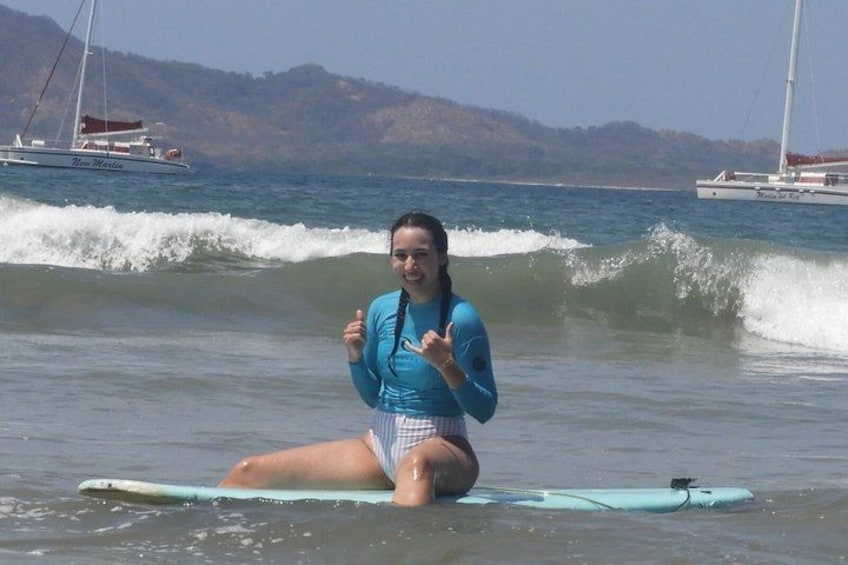 A person sitting on a surfboard in the ocean with boats in the background. 5