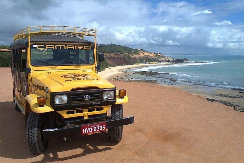 A yellow off-road vehicle parked on a beach with a license plate 'HVO-8395'. 3