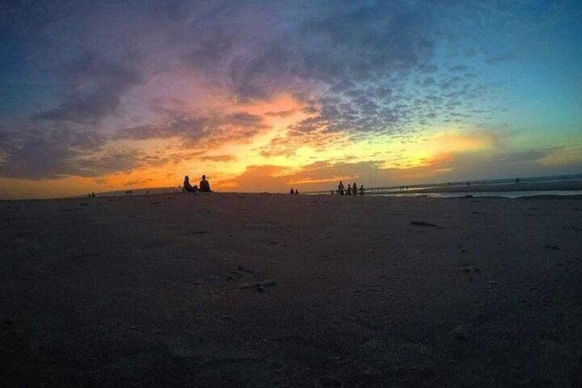 A beach at sunset with silhouettes of people and a clear sky. 3